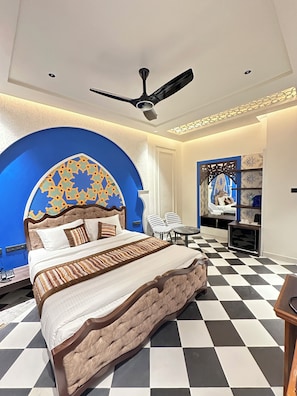 A modern hotel room with a large bed, a ceiling fan, a patterned wall, and a checkered floor. - Hotel Grand Kailash Haveli (Lansdowne)