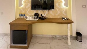 Un escritorio moderno con televisor integrado, un mueble pequeño y un cesto de basura.