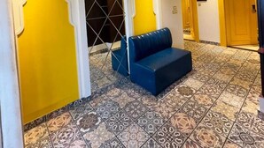 Un vestíbulo de hotel con suelo de baldosas estampadas, una zona de estar azulada y un ventilador de techo.