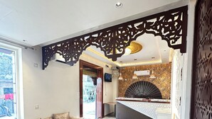 Una sala de estar moderna con sofá, reposapiés y una pequeña mesa redonda. Se aprecia un panel decorativo en el techo y un suelo estampado.