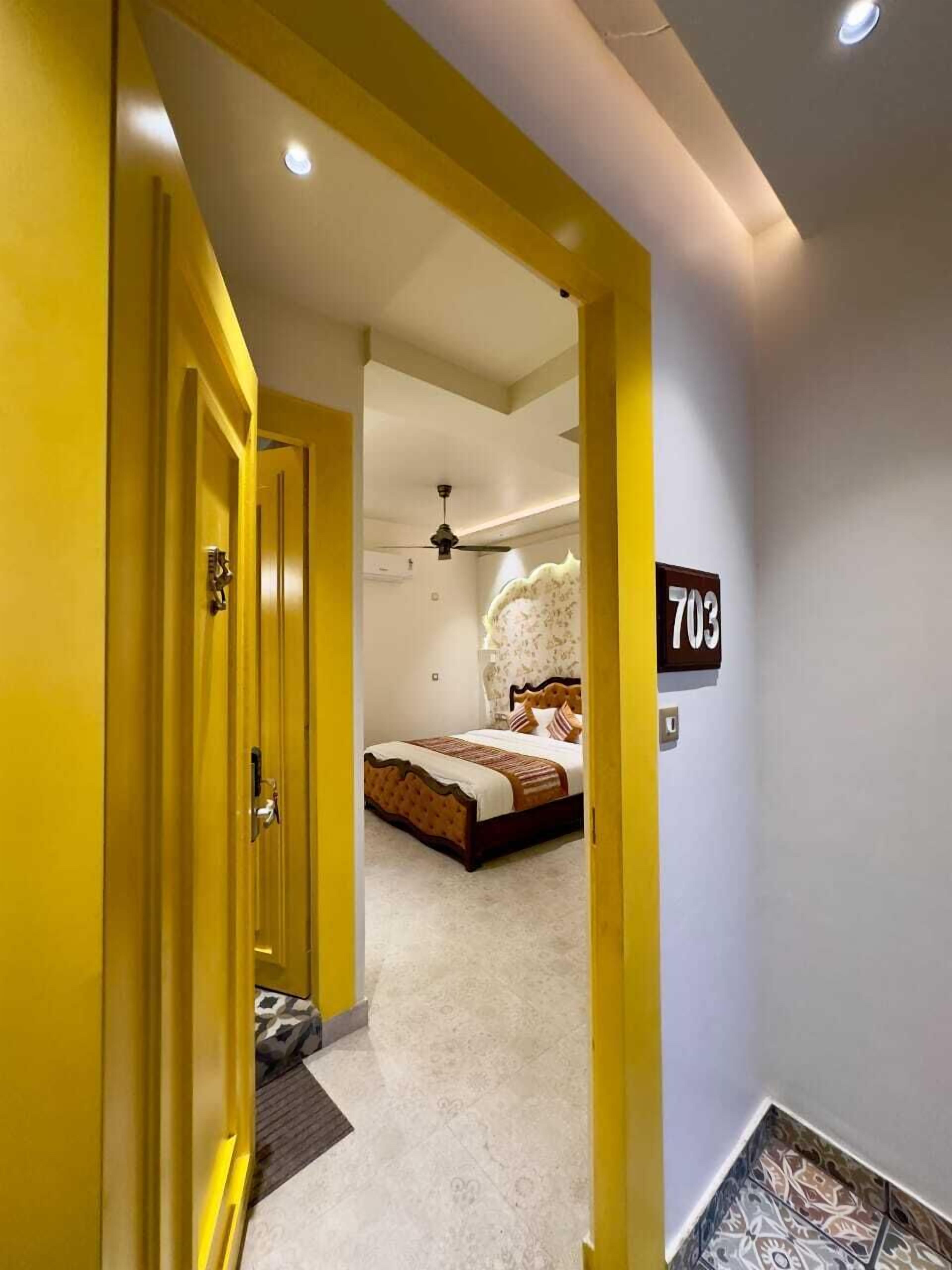 A hotel room with a bed, a ceiling fan, and a number sign indicating room 703.
