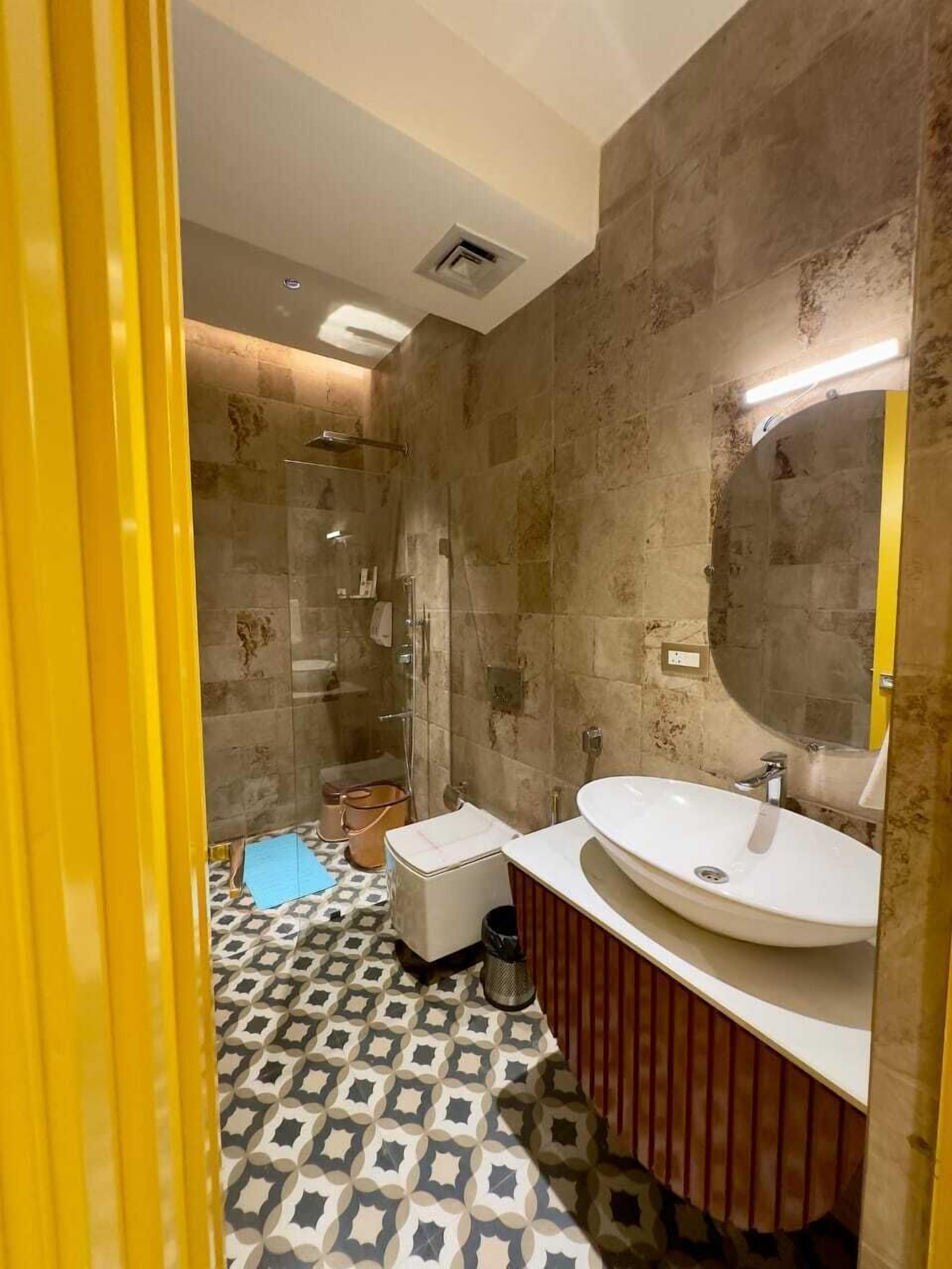 Un baño con ducha, dos lavamanos y piso estampado.