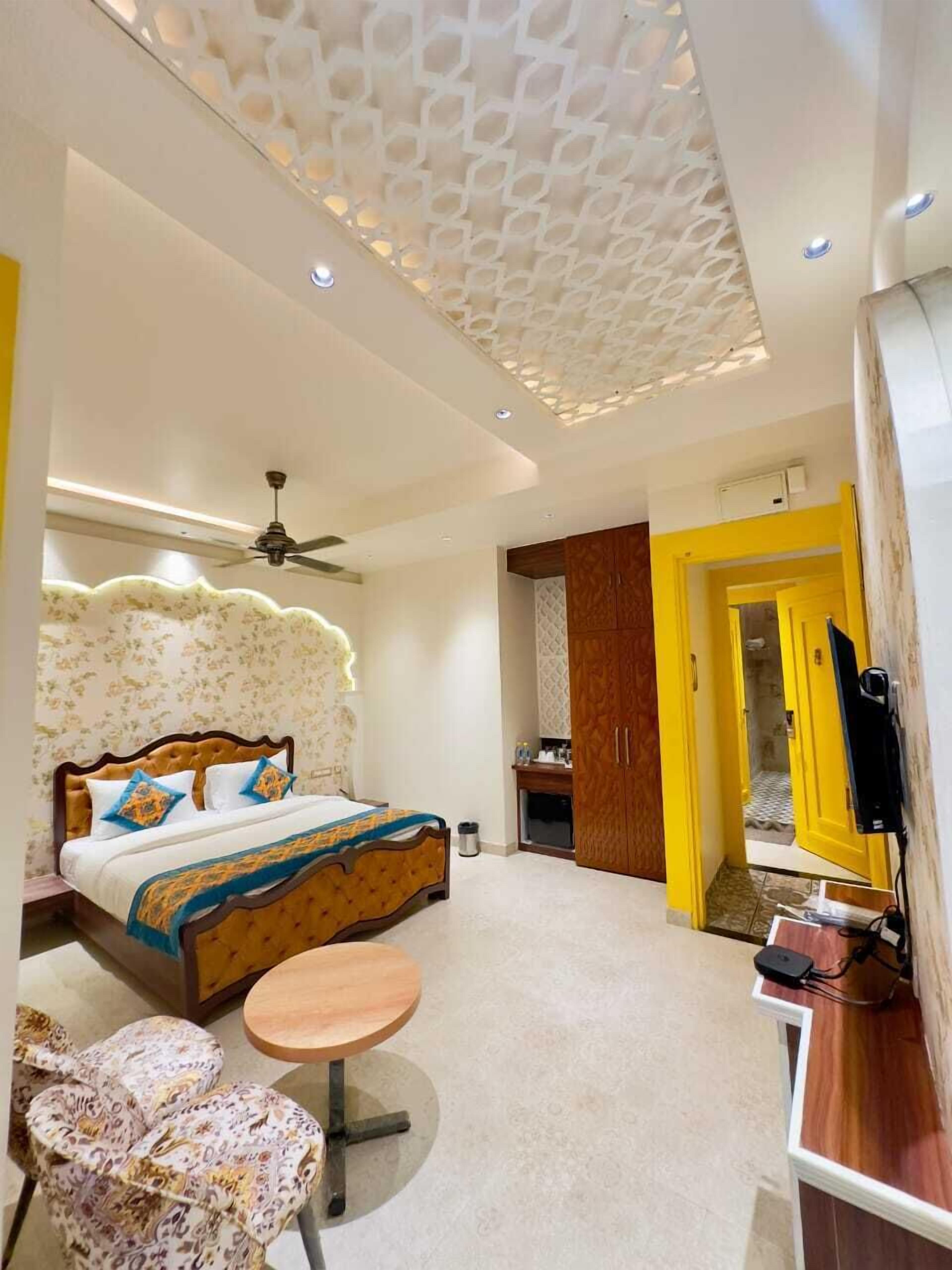 A modern hotel room with a bed, a small round table, a sofa, and a TV.