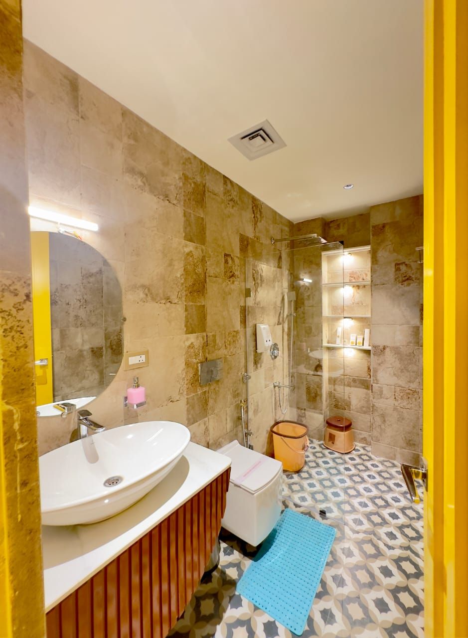 A modern bathroom with a large sink, a mirror, a shower enclosure, and patterned floor tiles.