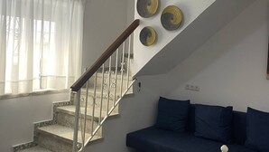 A staircase with a metal railing leading to a landing, a dark blue sofa, and three decorative plates on the wall. - Casa Blue in Torrox With 2 Bedrooms and 1 Bathrooms (Torrox)