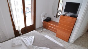 Ein Schlafzimmer mit einem Bett, einem Holzschrank, einem Fernseher und einem Ventilator.