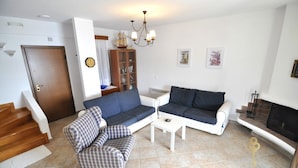 Ein Wohnzimmer mit Sofa, Sessel, Couchtisch und Kamin.
