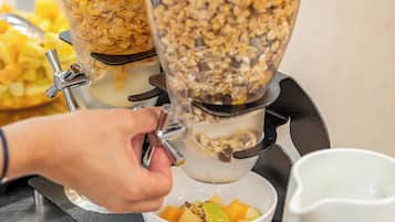 Un distributeur de boissons doté de deux récipients, l’un contenant des céréales à l’orange et l’autre, du granola.