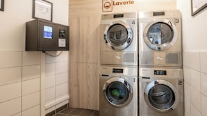 A laundry facility with four washing machines, a control panel, and a sign indicating "Laverie." - UCPA Sport Station Hostel Paris (Paris)
