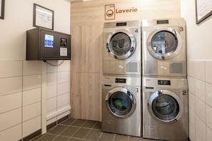 Un cuarto de lavandería con cuatro lavadoras, un panel de control y un letrero que dice 'Laverie'.