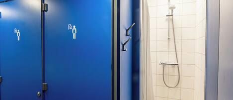 A public restroom with blue doors, a shower area, and a white tiled floor.