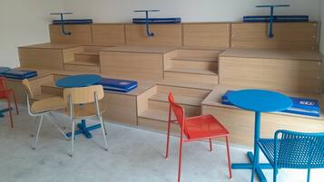 Un aula con pupitres, sillas y una mesa azul.