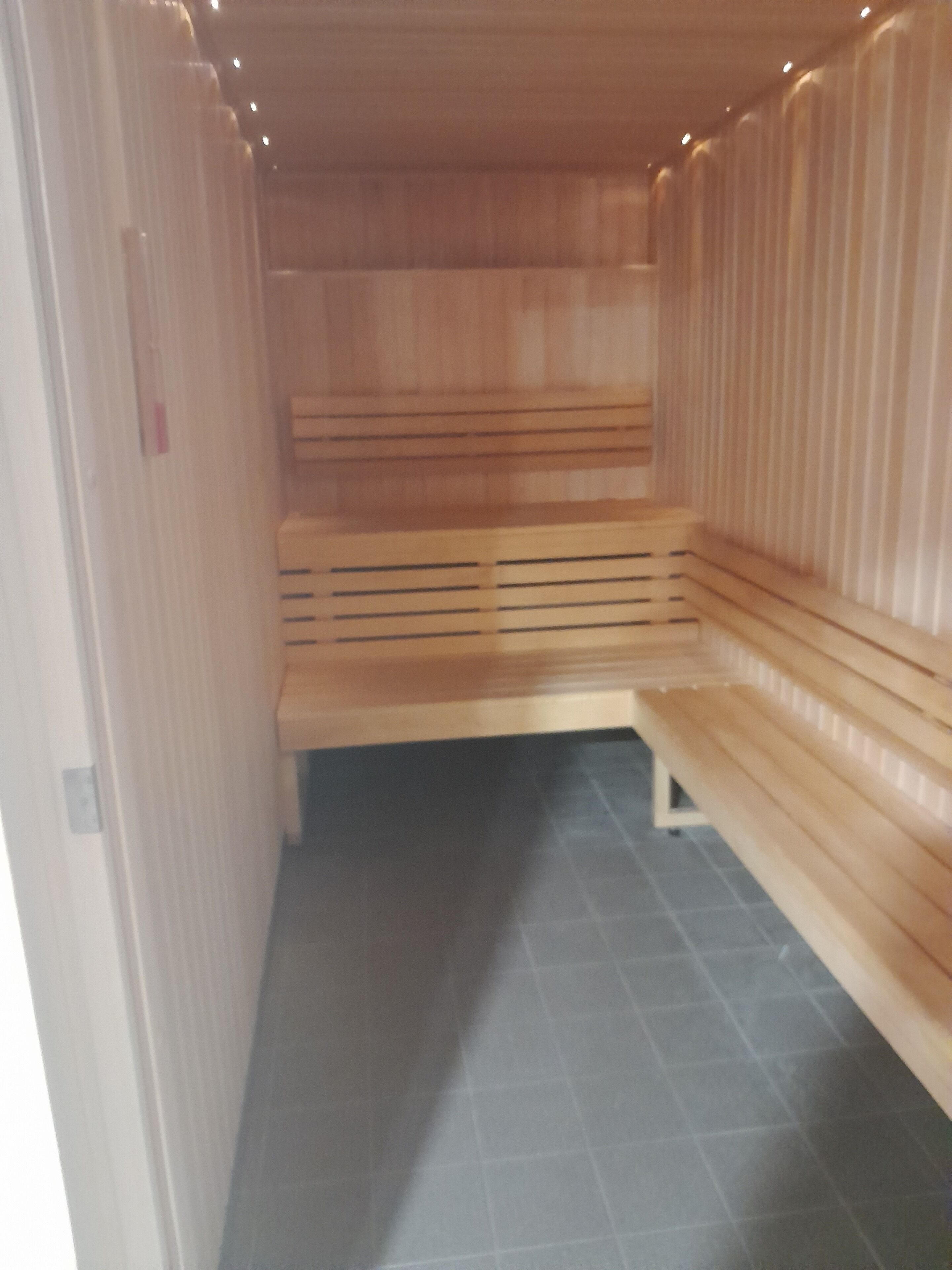 Un sauna avec des bancs en bois et un sol carrelé.