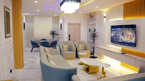 A modern living room with a sofa, armchairs, a coffee table, and a TV mounted on the wall. - Luxury 3 bedroom, Secure, Water View, 24/7 Power in secluded estate - Ikoyi  (Lagos)