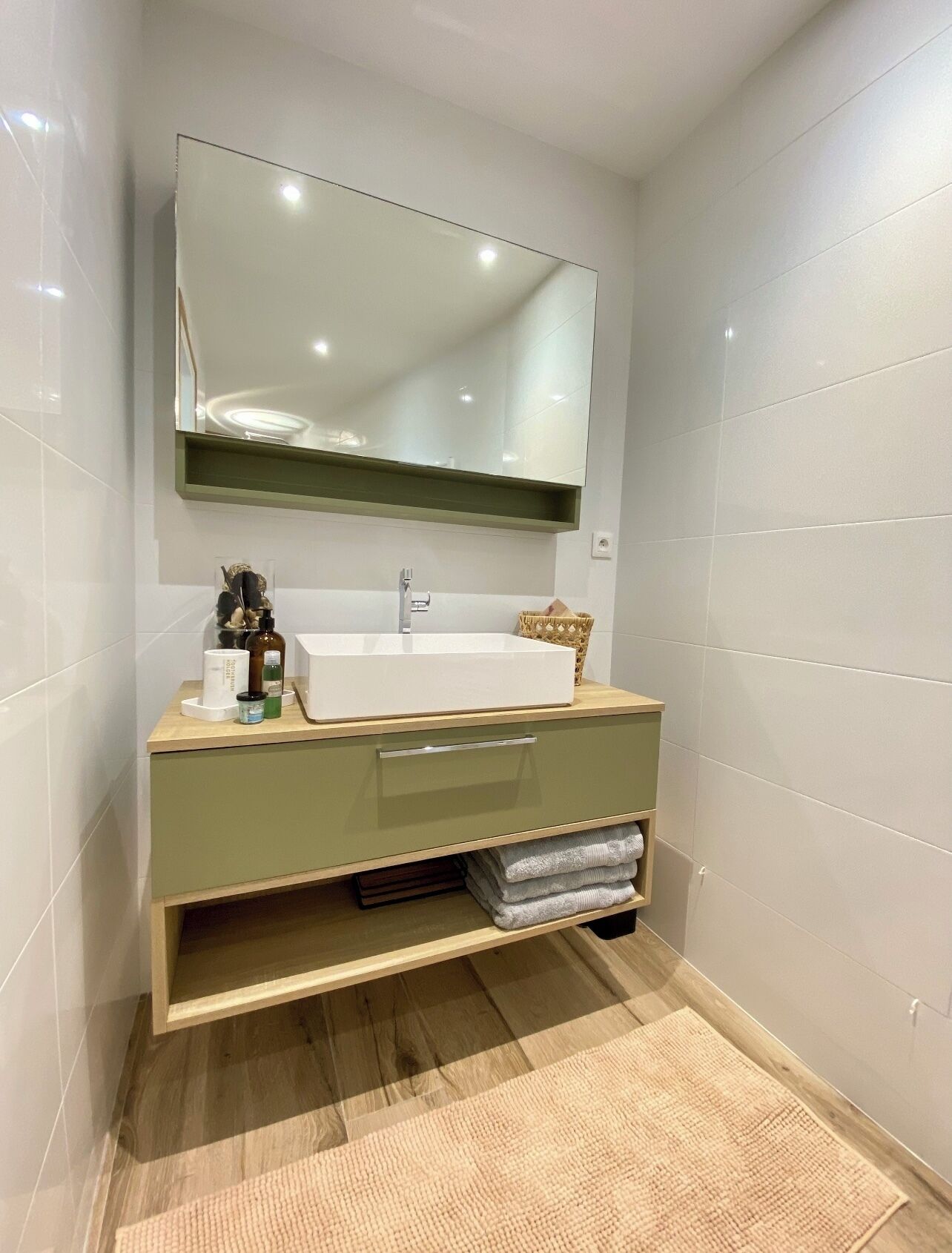 A modern bathroom with a white sink, a mirror above it, and a wooden vanity.