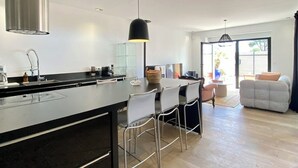 A modern kitchen with a central island, a dining area with chairs, and a living room with a sofa. - Apartment TY COSY in front of the beach of the blocked fort, calm and serenity.  (Ploemeur)