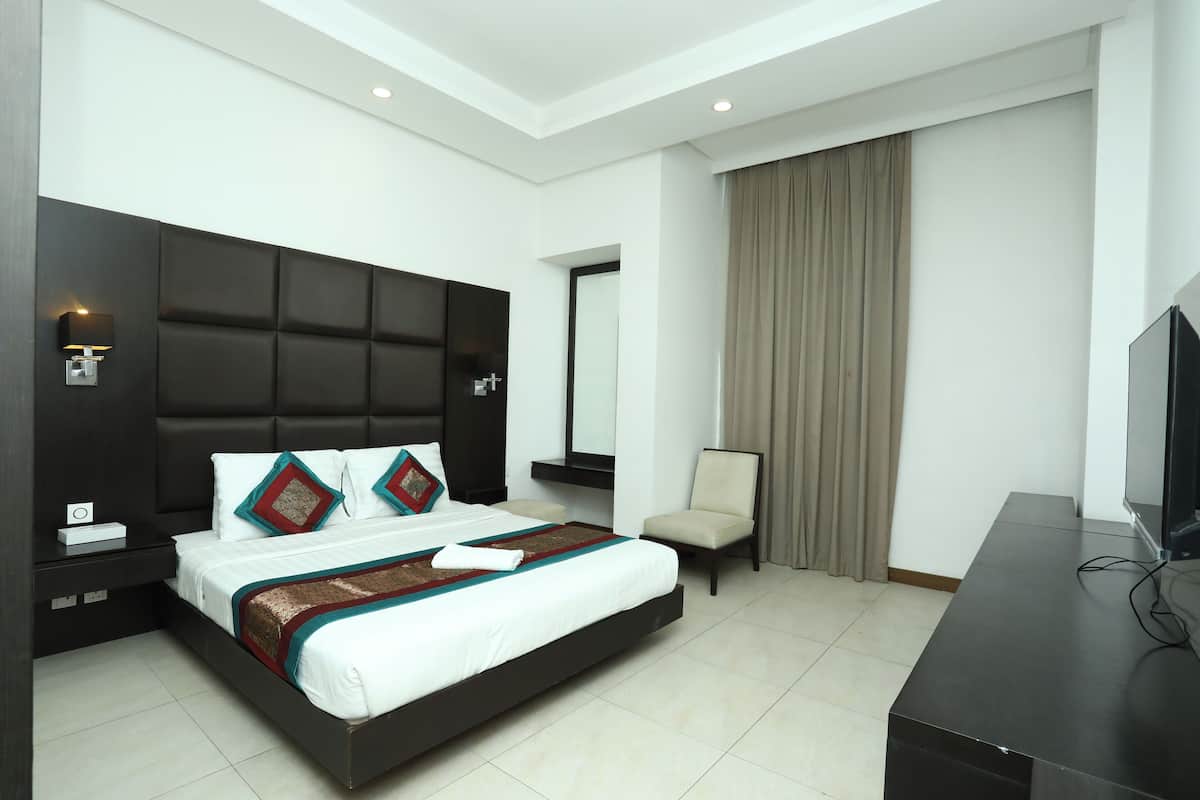 A modern hotel room with a large bed, a flat-screen TV, a desk, and a chair.