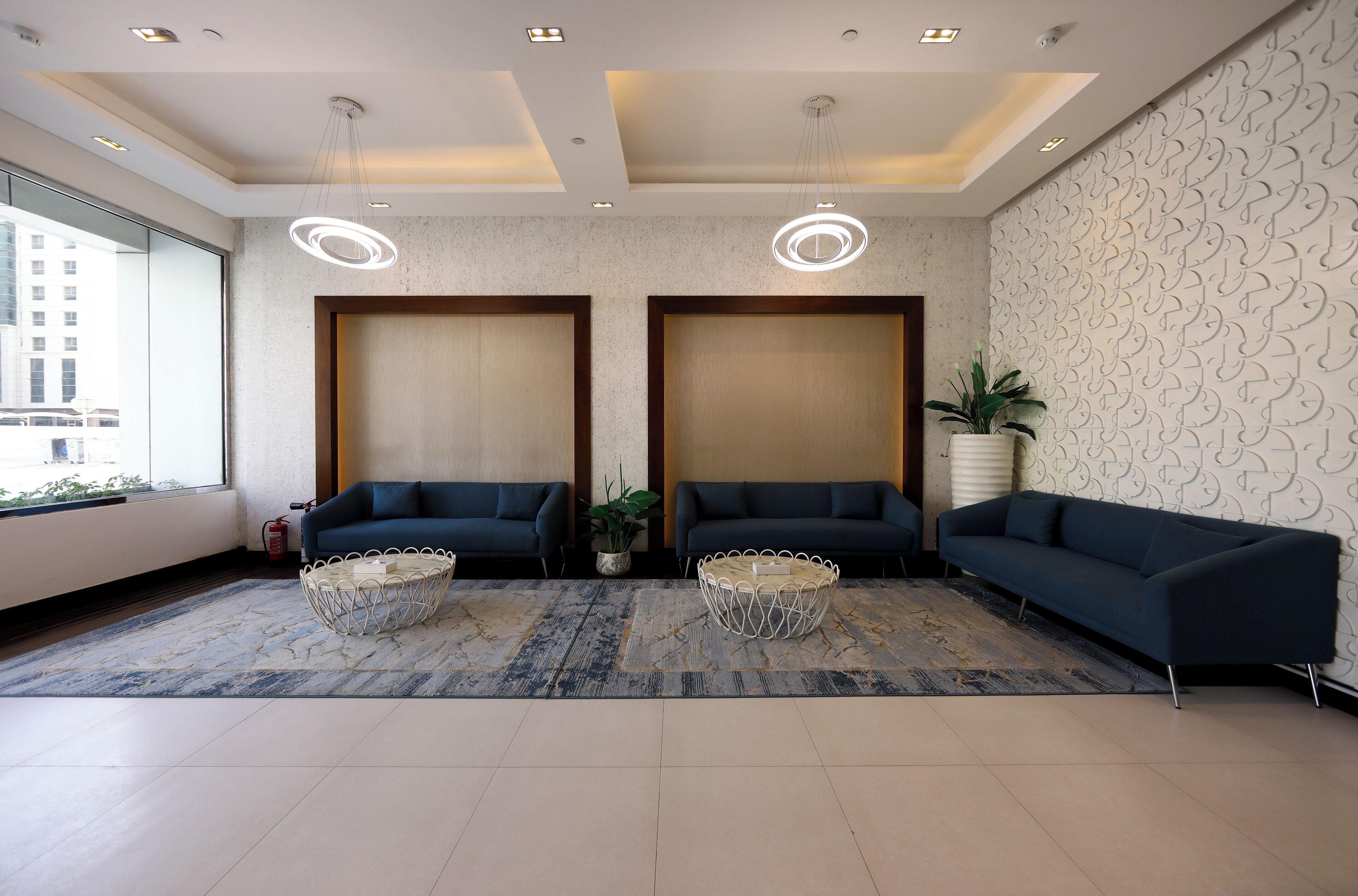 A modern lobby with two sofas, a round coffee table, and a patterned wall.
