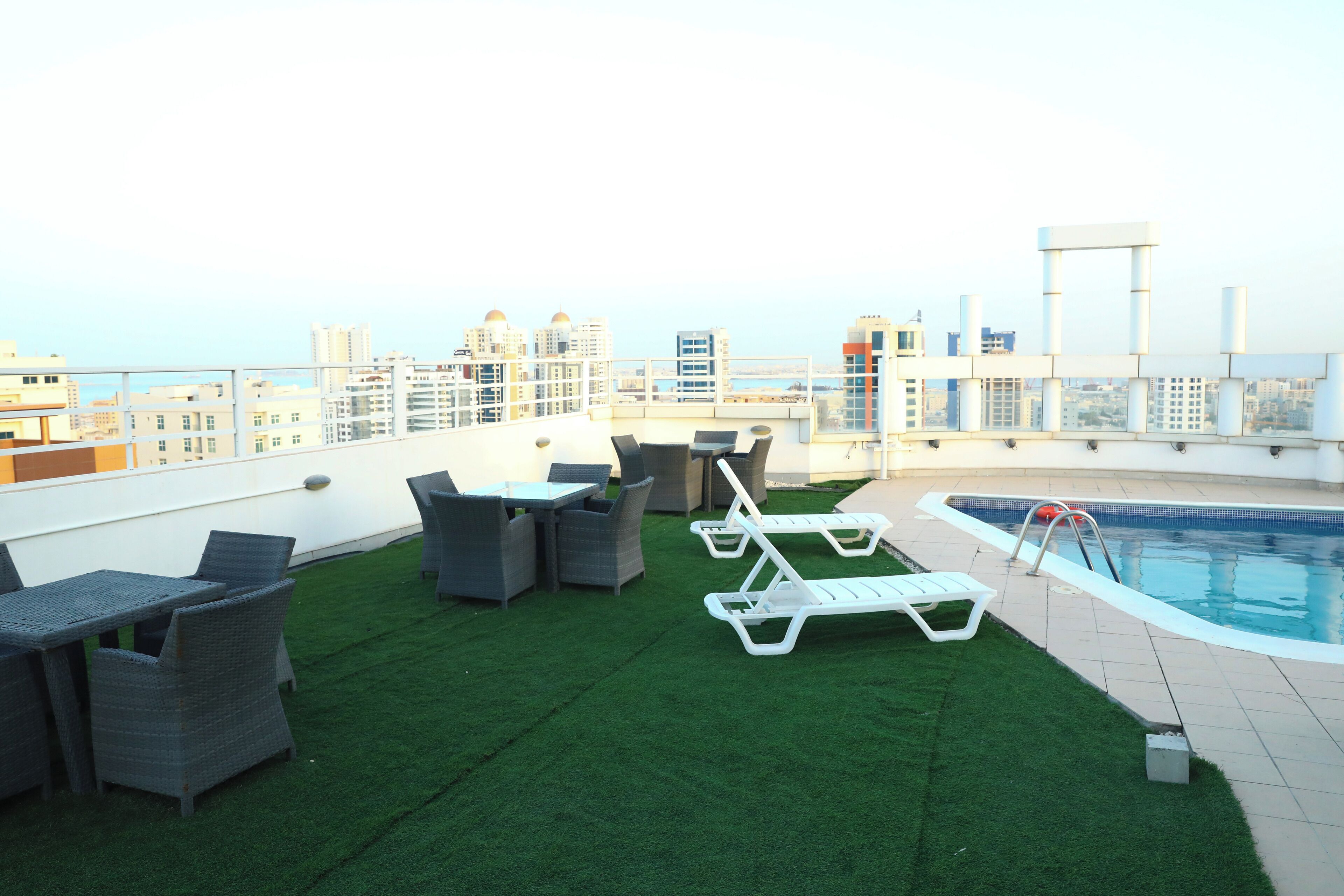 A rooftop terrace with artificial grass, lounge chairs, and a pool.