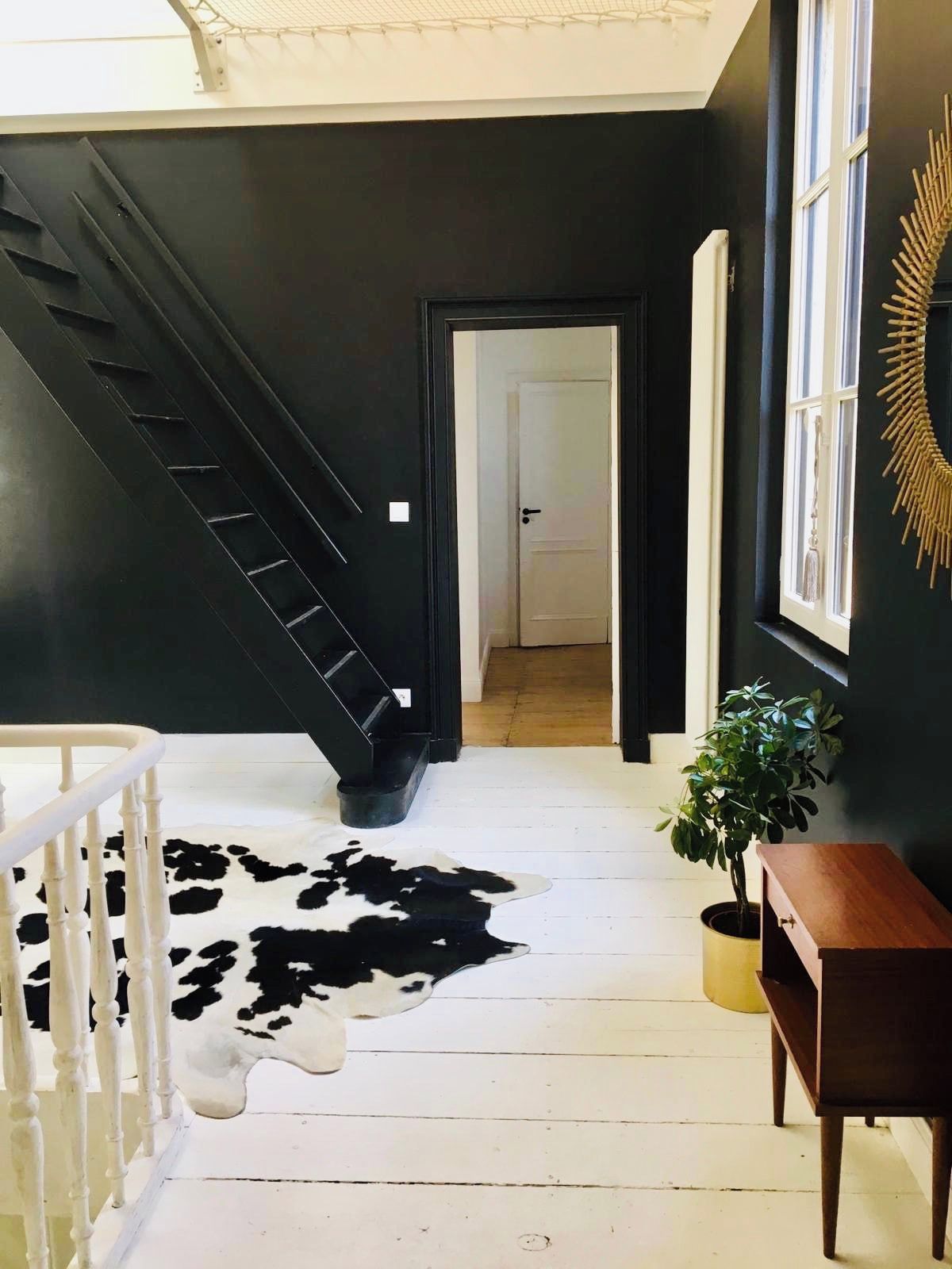 Una escalera conduce a una habitación con un tapete de cuero, un banco de madera y una planta en maceta.