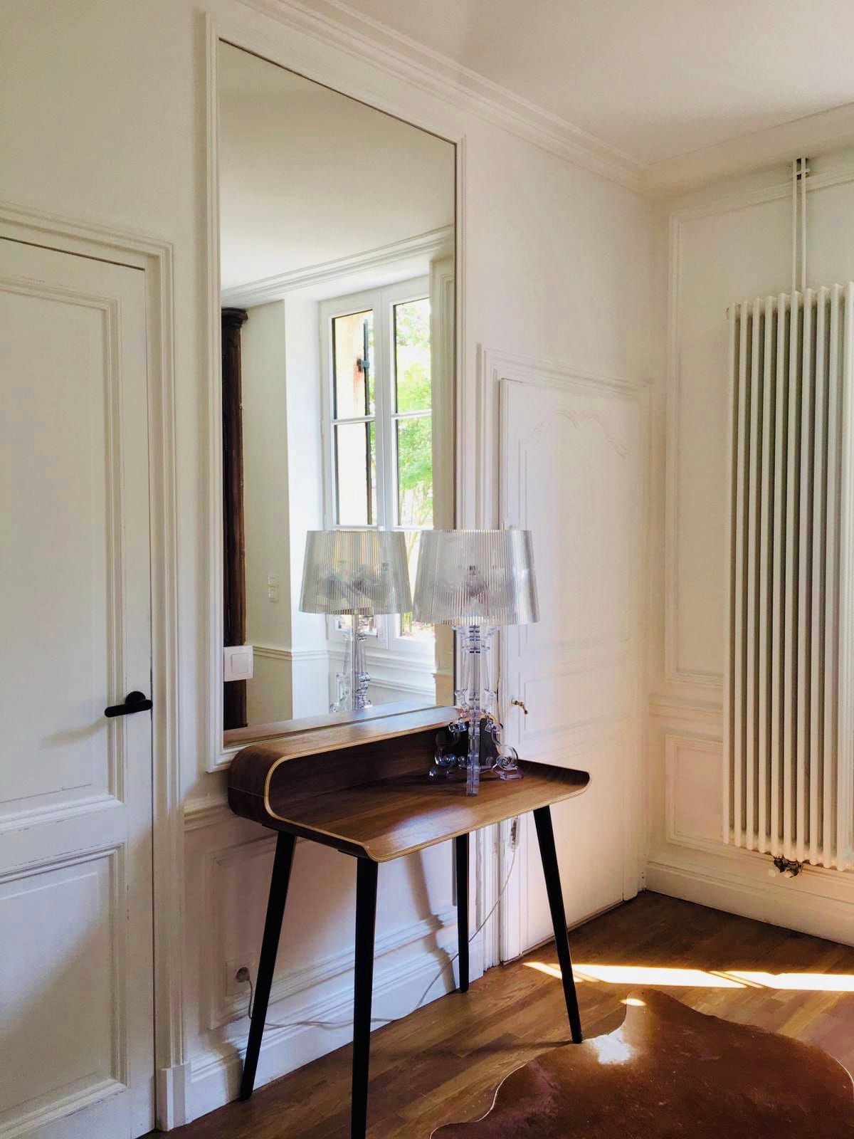 Una habitación con una mesa de madera, un espejo y un radiador.