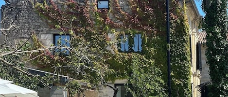 A stone building with a sloped roof, a small window, and a tree in the foreground.