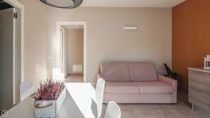 Una sala de estar moderna con un sofá, una mesa de comedor y una pequeña planta.