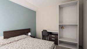 Un dormitorio con cama, escritorio y armario.