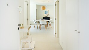 Un'area pranzo moderna e minimalista con un tavolo rotondo e sedie bianche, una lampada a sospensione e un quadro appeso al muro.