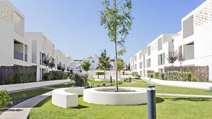 A modern residential complex with white buildings, a central circular garden, and a clear sky.