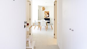 A modern interior with a dining area, white walls, and a large abstract painting.