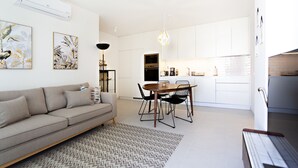 A modern living space with a sofa, dining table, chairs, and a kitchen area. - Modern, ideal for families (Cabanas de tavira)