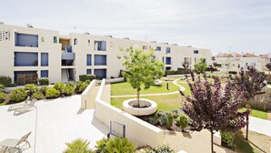 A modern residential building with multiple balconies, a landscaped courtyard with trees, and outdoor seating areas. - Modern, ideal for families (Cabanas de tavira)