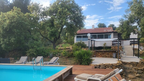 A swimming pool with lounge chairs, a stone wall, and a modern house in the background. - Villa Pour 7 Pers, 3 ch, Piscine Saint CYR SUR MER (Saint-Cyr-sur-Mer)