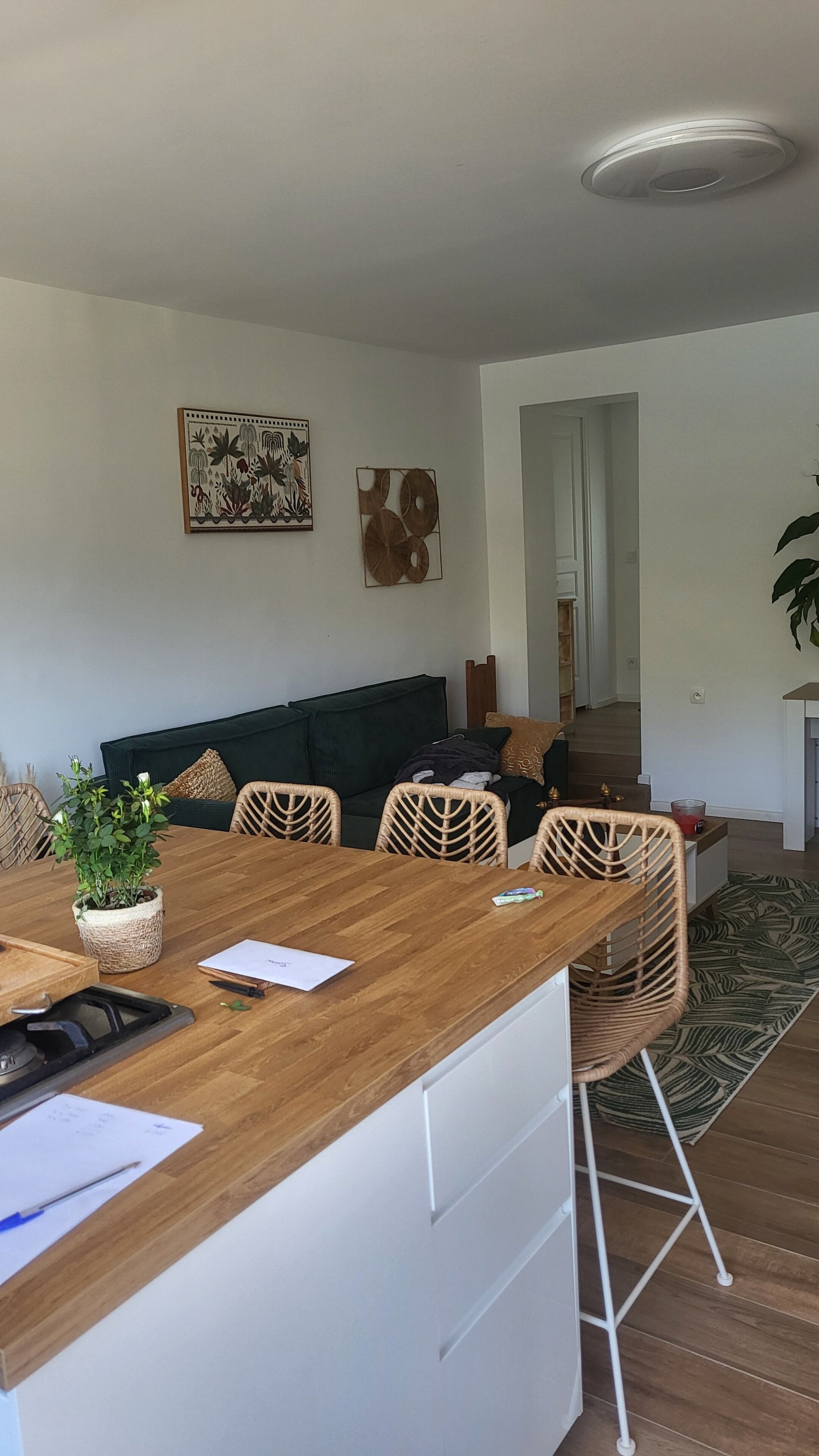 Uma cozinha moderna com bancada de madeira, armários brancos e uma área de refeições com cadeiras de vime.