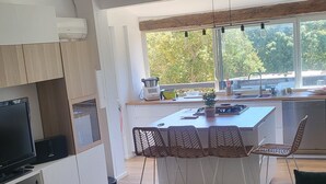 A modern kitchen with a dining area, a TV, and a coffee table. - Villa Pour 7 Pers, 3 ch, Piscine Saint CYR SUR MER (Saint-Cyr-sur-Mer)