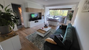 A modern living room with a TV, sofa, coffee table, and a dining area with chairs and a table. - Villa Pour 7 Pers, 3 ch, Piscine Saint CYR SUR MER (Saint-Cyr-sur-Mer)