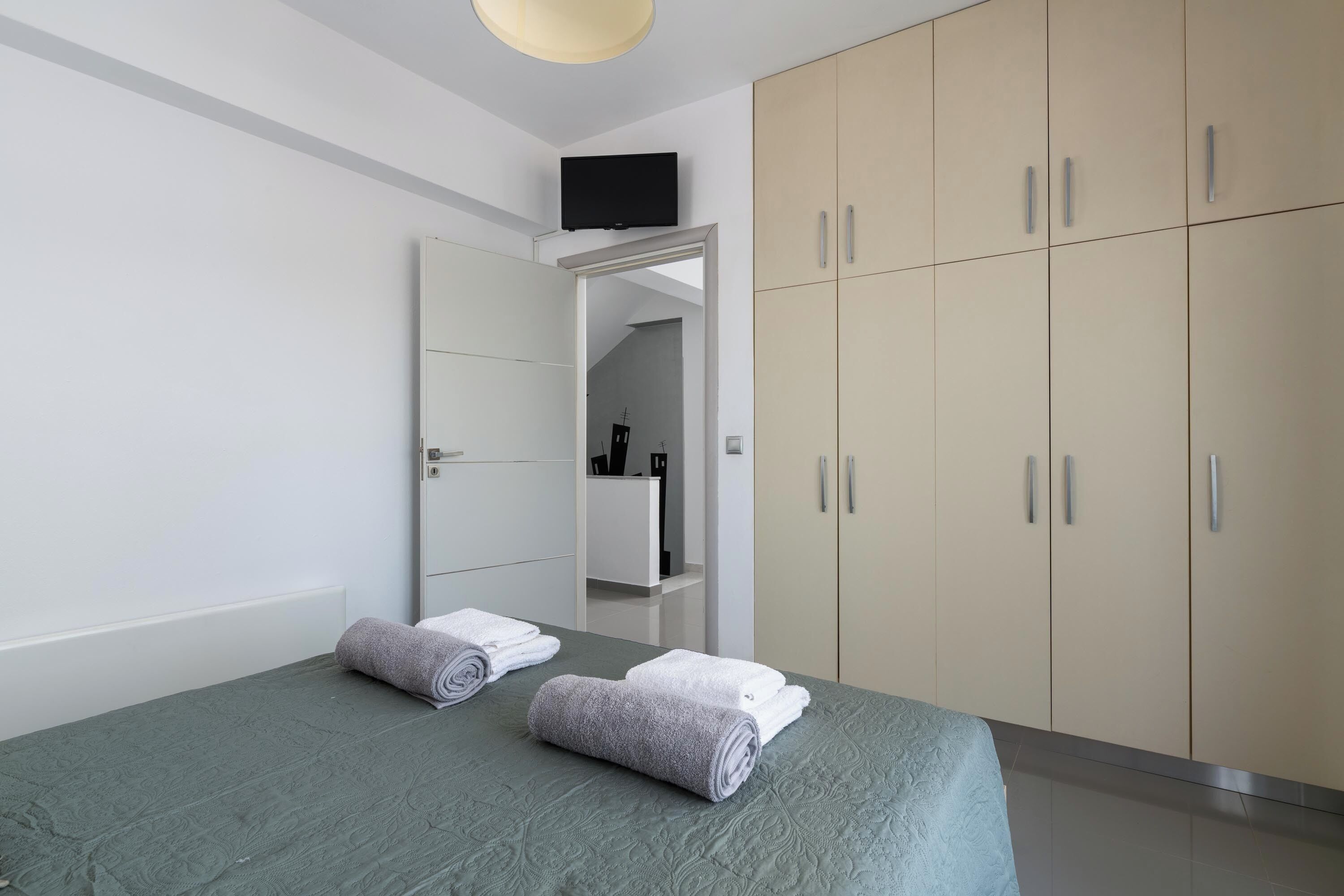 Une chambre d’hôtel moderne équipée d’un lit, d’un téléviseur fixé au mur et d’une armoire.