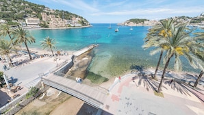 Un poble costaner amb aigües blaves cristal·lines, palmeres i un pont per a vianants.