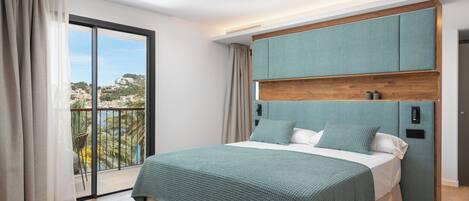 A bedroom with a large bed, a view of the city, and a balcony.