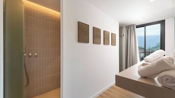 Un baño moderno con ducha, bañera y tocador con toallas. Hay cuatro cuadros enmarcados en la pared y un ventanal con vistas.