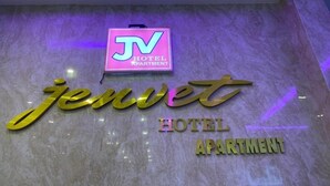Een hotelschild met de naam 'Jenwet' en 'Hotel Apartment' in gouden letters op een marmeren muur.