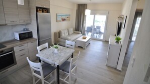 A modern kitchen with a marble table, white chairs, a sofa, and a dining area. - Zennova 60 Nikiti Family Apt (Sithonia)