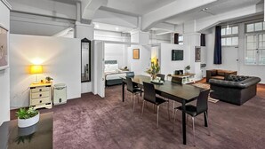 A spacious room with a dining table, chairs, a sofa, and a bed. - Maison Marvel l Enormous Loft Apt l Heart of City (Auckland)