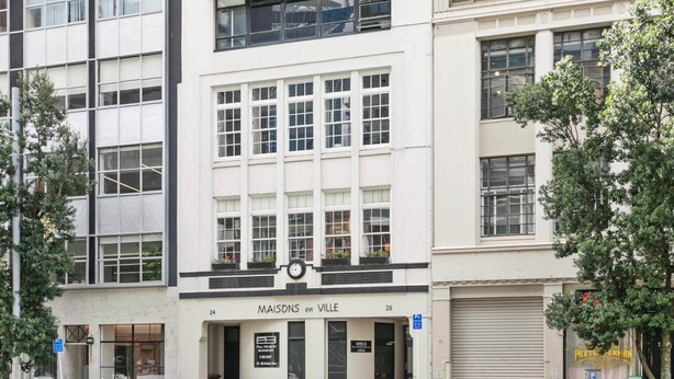 A building with a white facade, multiple windows, and a sign reading "MAISONS en VILLE". - Maison Marvel l Enormous Loft Apt l Heart of City (Auckland)
