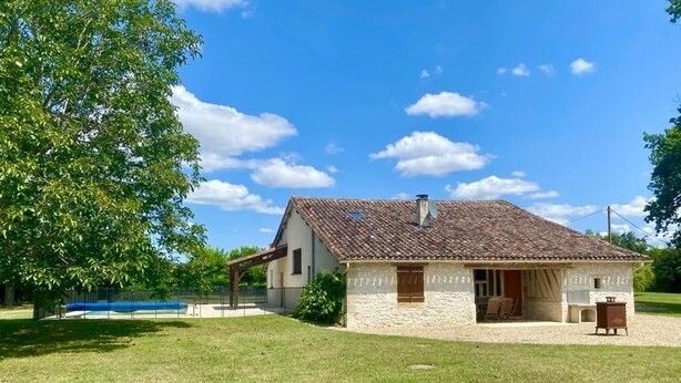 A two-story stone house with a tiled roof, a covered patio, and a small garden. - Stylish barn conversion  with a beautiful pool and stunning 4ha grounds. (Moustier)