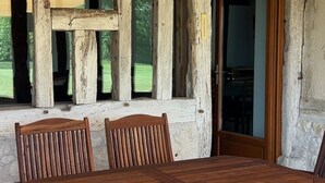 A rustic wooden dining area with a large table and chairs, a hanging light fixture, and a view of the outdoors. - Stylish barn conversion  with a beautiful pool and stunning 4ha grounds. (Moustier)