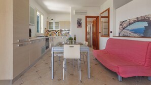 Una cocina moderna con comedor, un sofá rojo y vistas al mar.