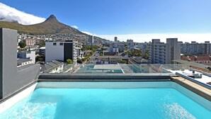 Una piscina sul tetto con vista sulla città e su una montagna.