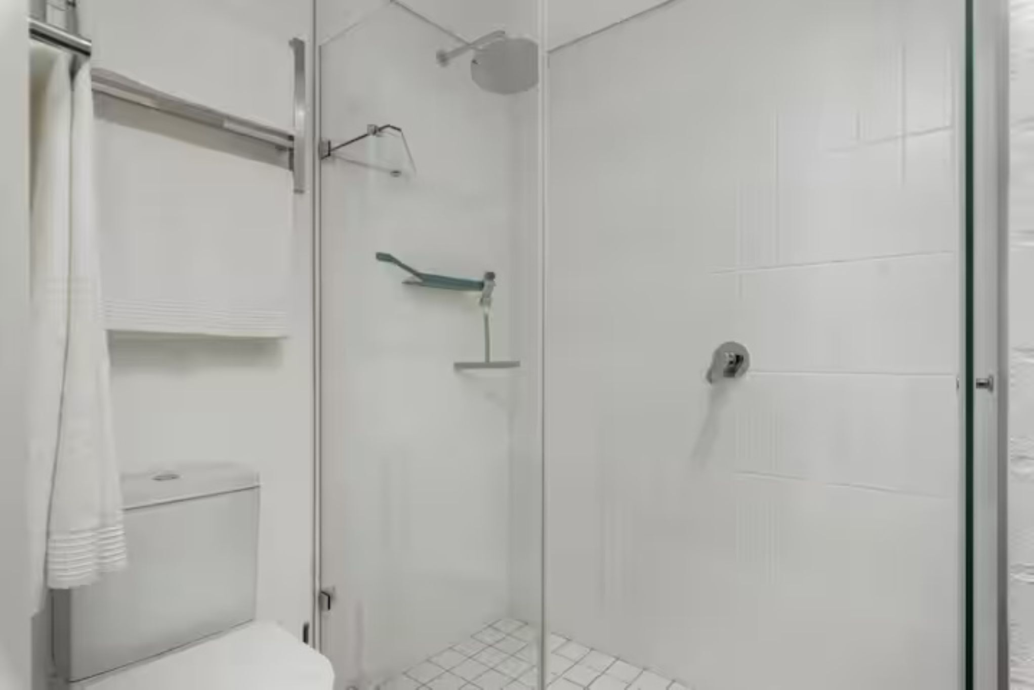 Ein modernes Badezimmer mit Duschkabine aus Glas, Toilette und Handtuchhalter.